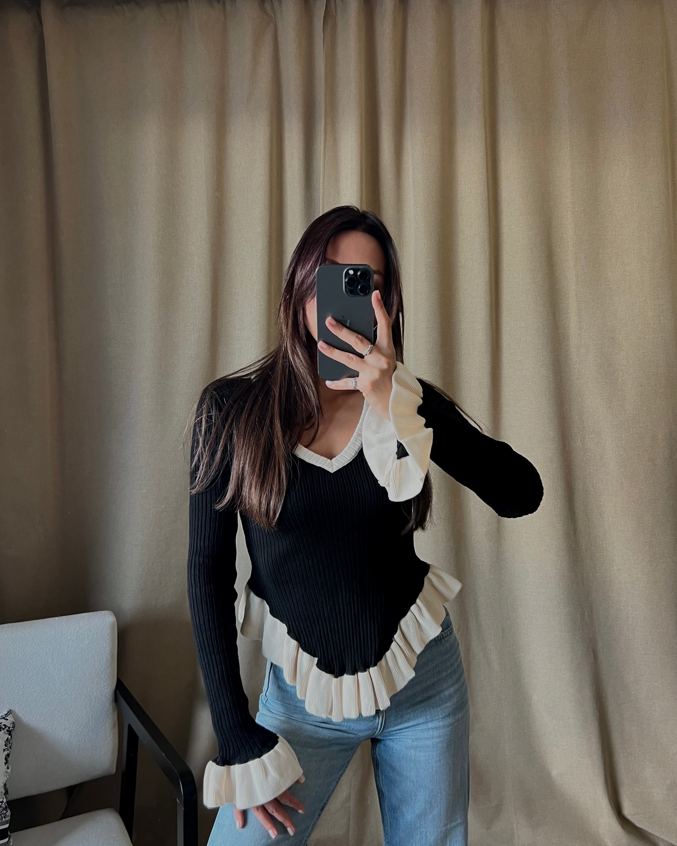 V-neck white sweater with ruffle detail in black.