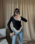 V-neck white sweater with ruffle detail in black.